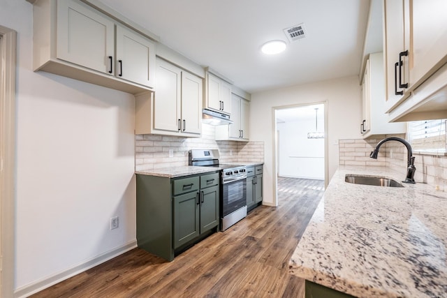 kitchen featuring dark wood-type flooring, sink, green cabinetry, decorative backsplash, and stainless steel range with gas cooktop