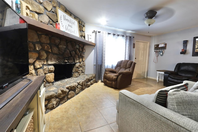 living room with ceiling fan, a fireplace, crown molding, and light tile patterned floors