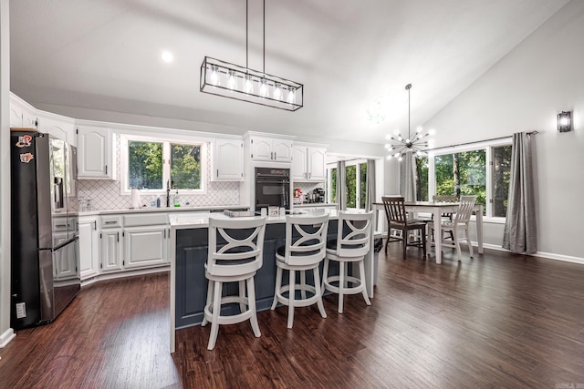 kitchen featuring a kitchen island, dark wood-type flooring, white cabinetry, stainless steel refrigerator, and a wealth of natural light