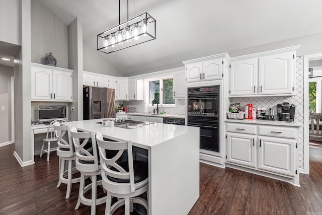 kitchen featuring a kitchen island, black appliances, plenty of natural light, and white cabinetry