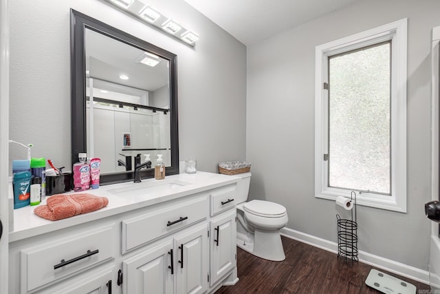 bathroom with vanity, hardwood / wood-style flooring, a shower with door, a healthy amount of sunlight, and toilet