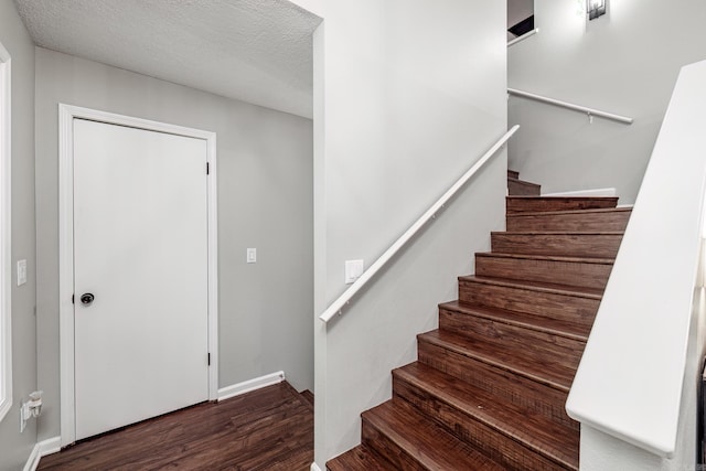 staircase with wood-type flooring and a textured ceiling