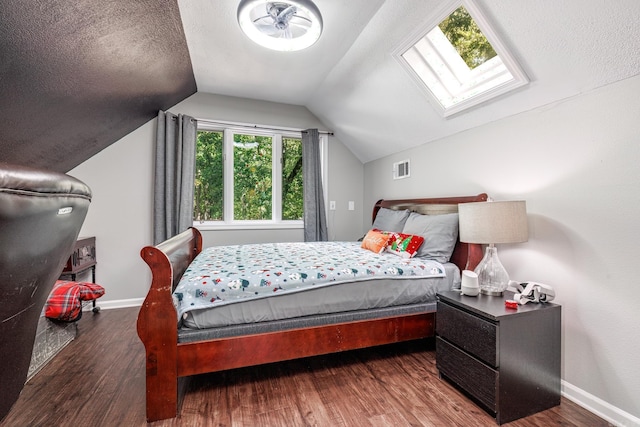 bedroom featuring lofted ceiling with skylight, a textured ceiling, and dark hardwood / wood-style flooring