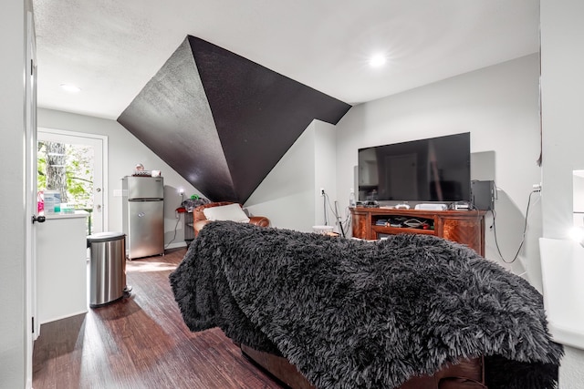 bedroom with stainless steel fridge, dark wood-type flooring, vaulted ceiling, and a textured ceiling