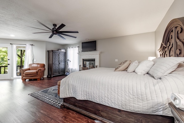 bedroom with access to outside, ceiling fan, a brick fireplace, a textured ceiling, and dark hardwood / wood-style flooring