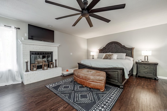 bedroom featuring a fireplace, dark hardwood / wood-style floors, a textured ceiling, and ceiling fan