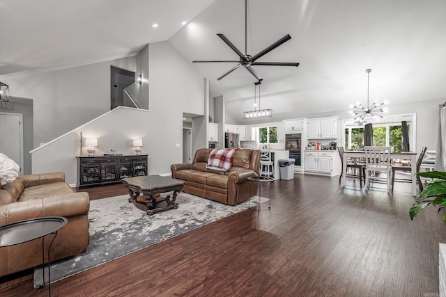 living room featuring ceiling fan with notable chandelier, high vaulted ceiling, plenty of natural light, and dark wood-type flooring