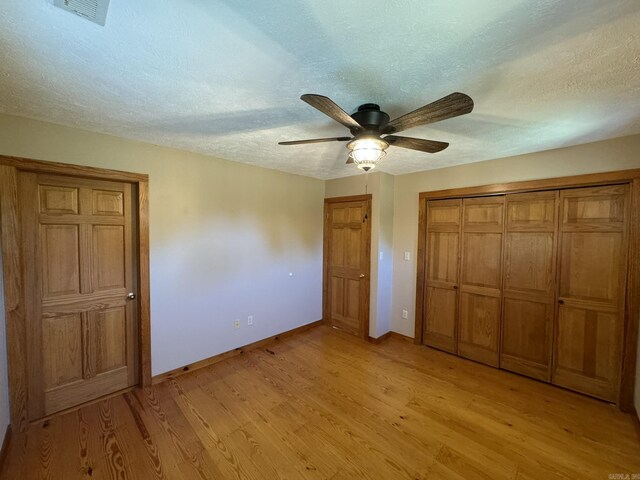 unfurnished bedroom with a closet, baseboards, a textured ceiling, visible vents, and light wood finished floors