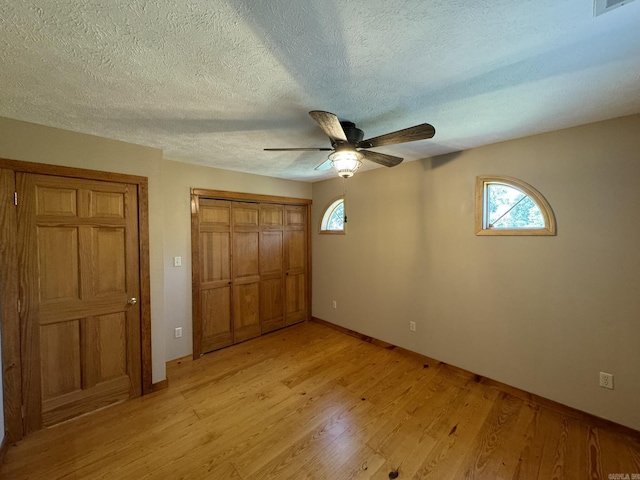 unfurnished bedroom featuring a closet, multiple windows, light wood-type flooring, and baseboards