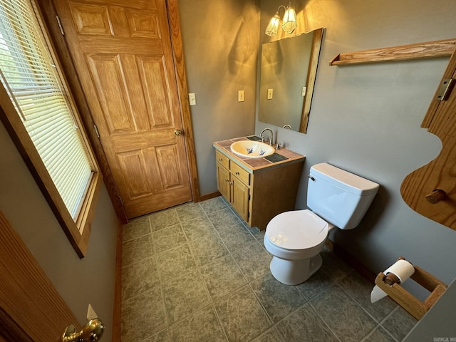 bathroom with toilet, vanity, a wealth of natural light, and baseboards