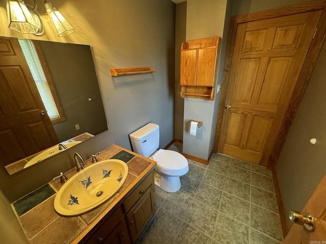 bathroom featuring toilet, vanity, and baseboards