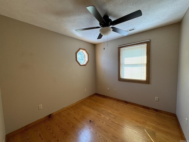 spare room with visible vents, light wood-type flooring, a textured ceiling, and ceiling fan