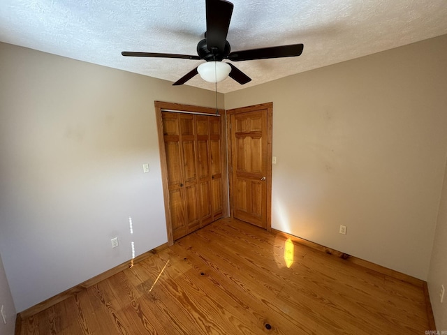 unfurnished bedroom with a closet, baseboards, a textured ceiling, a ceiling fan, and light wood finished floors