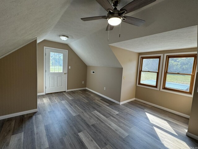 bonus room with baseboards, ceiling fan, dark wood finished floors, a textured ceiling, and vaulted ceiling