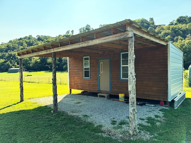 view of outbuilding featuring a carport, fence, and an outbuilding