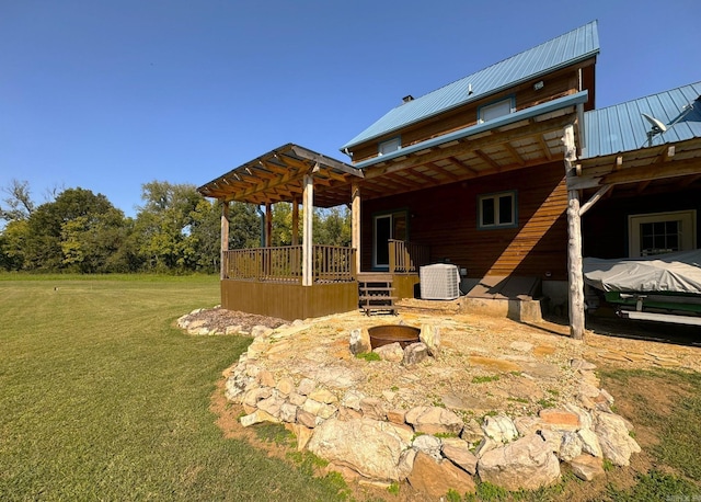 rear view of property featuring a pergola, a wooden deck, central AC, a yard, and metal roof