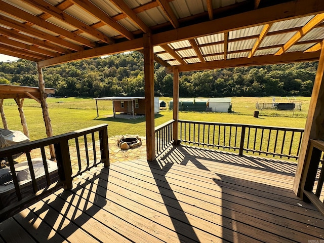 wooden deck with a yard, an outdoor fire pit, and an outbuilding