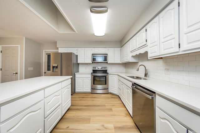 kitchen with stainless steel appliances, sink, light wood-type flooring, and white cabinetry