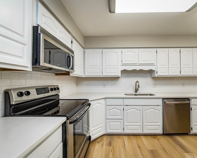 kitchen with tasteful backsplash, light hardwood / wood-style flooring, sink, appliances with stainless steel finishes, and white cabinetry