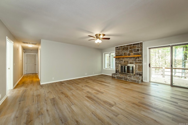 unfurnished living room with light wood-type flooring, a fireplace, ceiling fan, and a textured ceiling