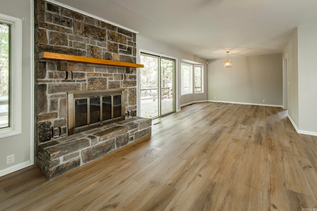 unfurnished living room with wood-type flooring, a wealth of natural light, and a stone fireplace