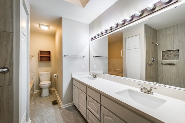 bathroom featuring a tile shower, vanity, and toilet