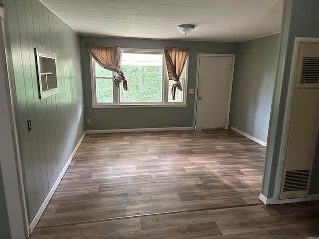 unfurnished room featuring wood-type flooring and wooden walls