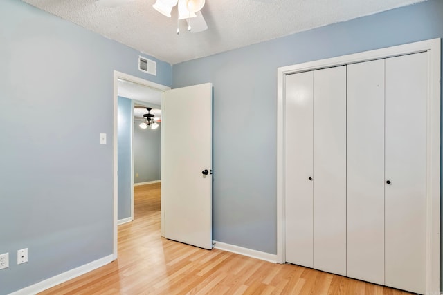 unfurnished bedroom featuring a closet, light hardwood / wood-style floors, a textured ceiling, and ceiling fan