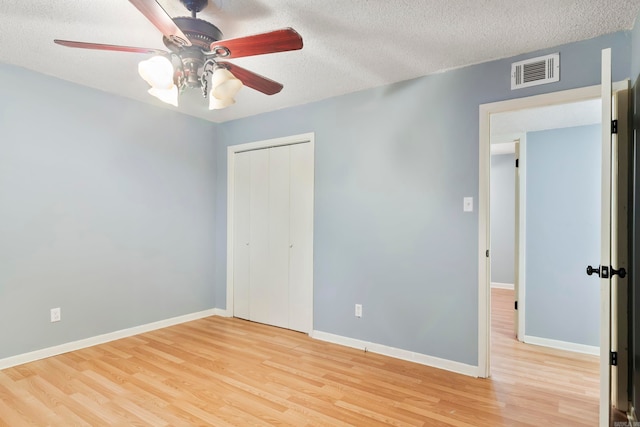 unfurnished bedroom featuring a textured ceiling, a closet, light wood-type flooring, and ceiling fan