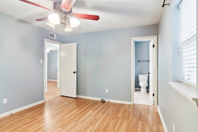 unfurnished bedroom with light hardwood / wood-style floors, ensuite bathroom, a textured ceiling, and ceiling fan