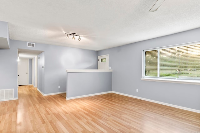 empty room with a textured ceiling and light wood-type flooring