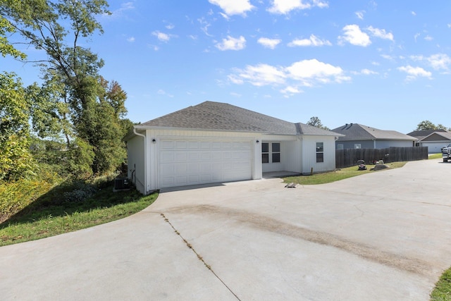 single story home with cooling unit and a garage