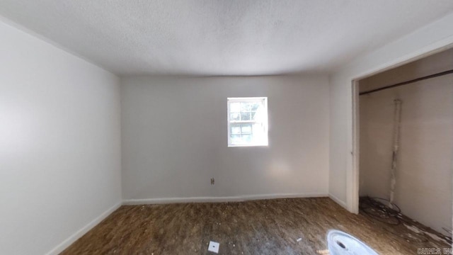 unfurnished bedroom with a textured ceiling, a closet, and dark hardwood / wood-style flooring