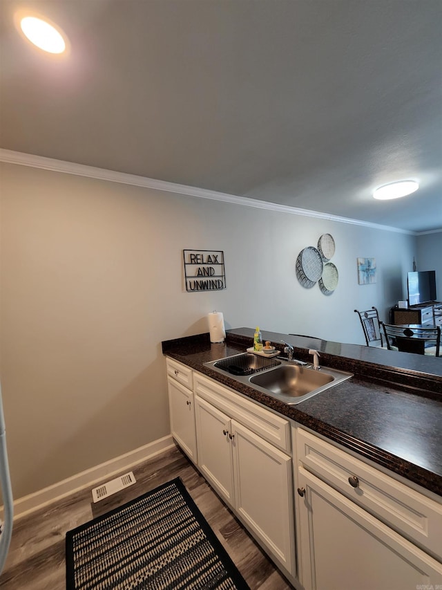 kitchen with ornamental molding, dark wood-type flooring, white cabinetry, and sink