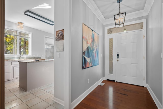 entryway featuring sink, crown molding, light hardwood / wood-style floors, and a chandelier