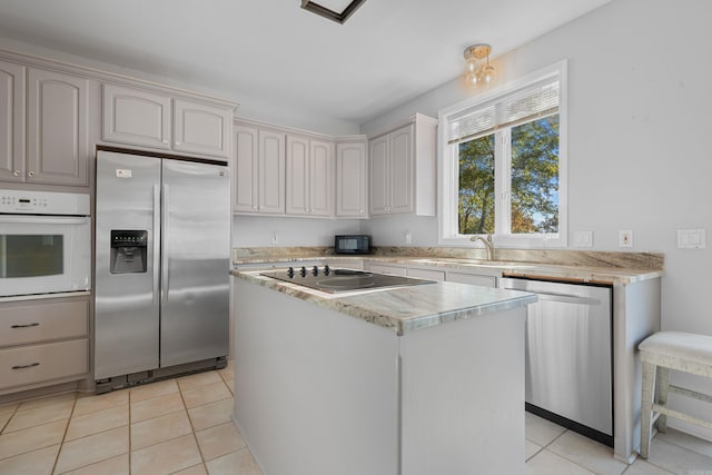 kitchen with sink, appliances with stainless steel finishes, light tile patterned floors, and a center island