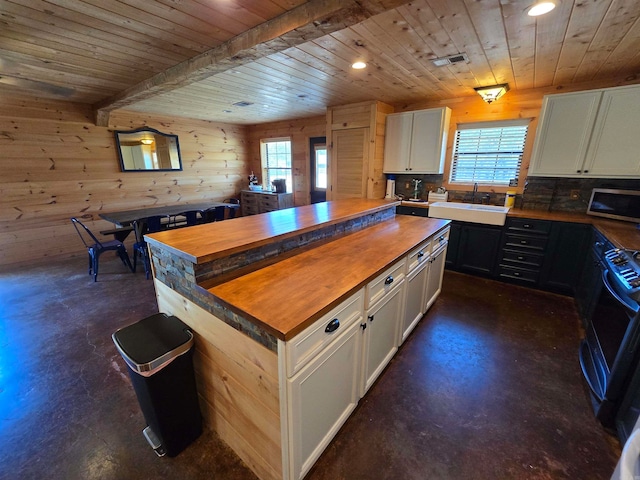 kitchen with wooden walls, white cabinetry, wood ceiling, and a wealth of natural light