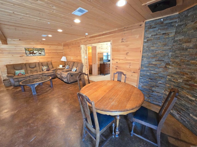 dining space featuring wood walls, concrete floors, and wooden ceiling