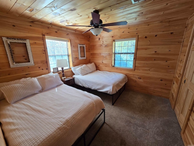 bedroom with ceiling fan, wooden walls, wood ceiling, and carpet