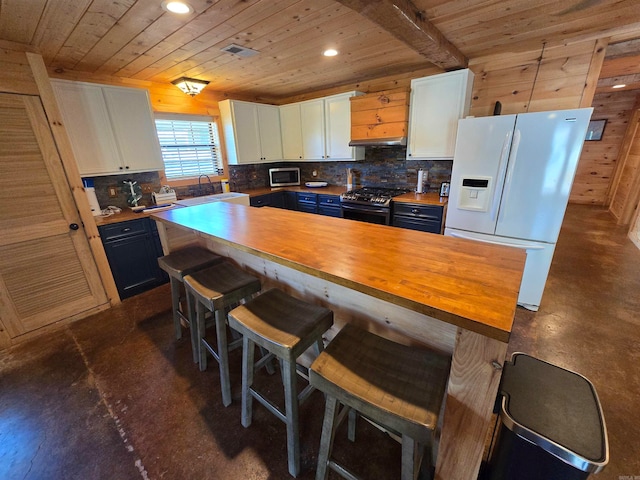 kitchen featuring white cabinets, sink, wooden counters, stainless steel appliances, and a breakfast bar