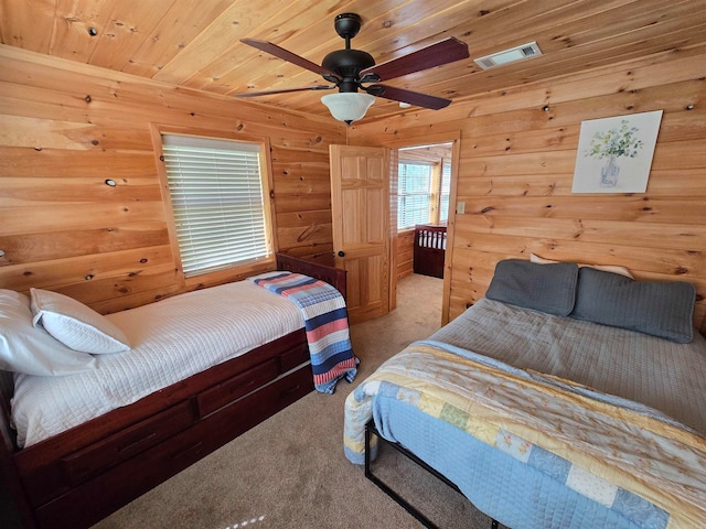 carpeted bedroom featuring ceiling fan, wood ceiling, and wood walls