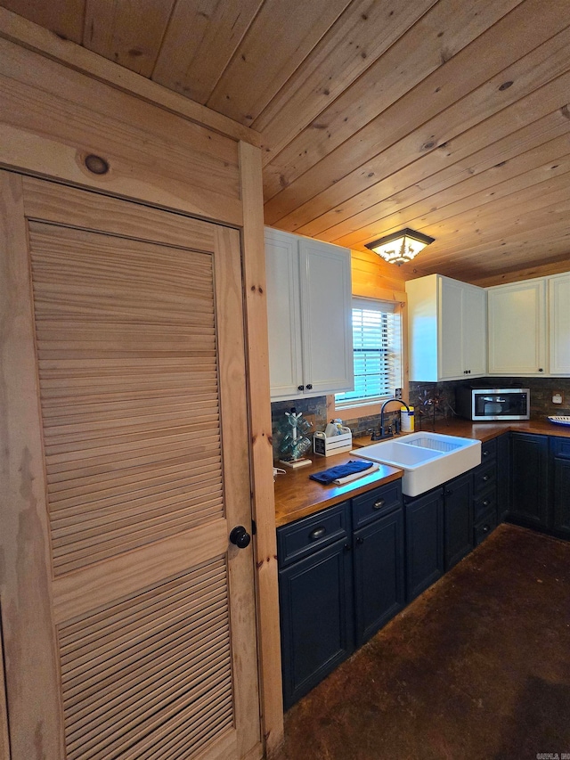 kitchen featuring tasteful backsplash, white cabinetry, sink, and wooden ceiling