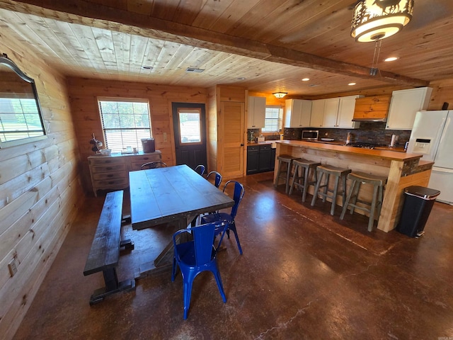 dining area featuring wood ceiling and wood walls