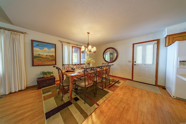 dining room with a notable chandelier, light hardwood / wood-style flooring, and a textured ceiling