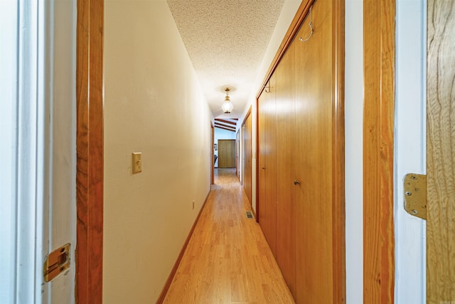 corridor featuring light hardwood / wood-style floors and a textured ceiling