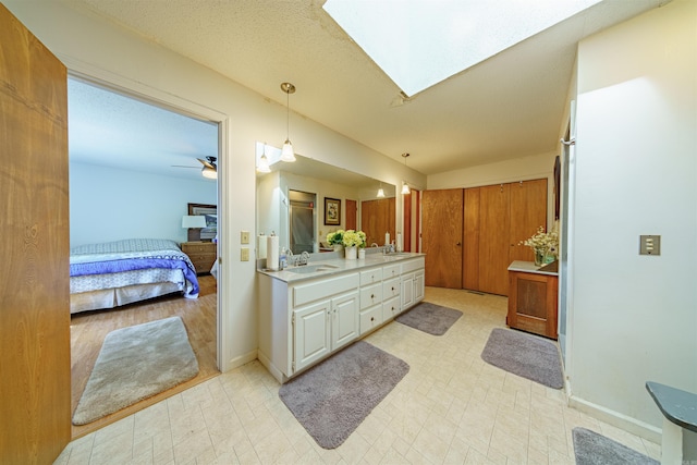 bathroom with a skylight, ceiling fan, and vanity