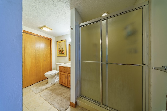 bathroom featuring vanity, tile patterned flooring, a shower with shower door, toilet, and a textured ceiling