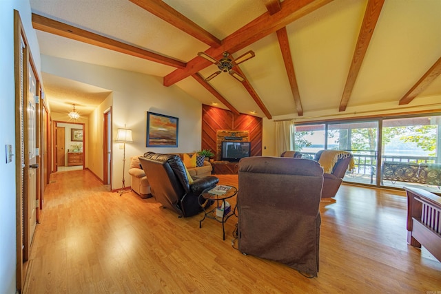 living room featuring wood walls, lofted ceiling with beams, light wood-type flooring, and ceiling fan