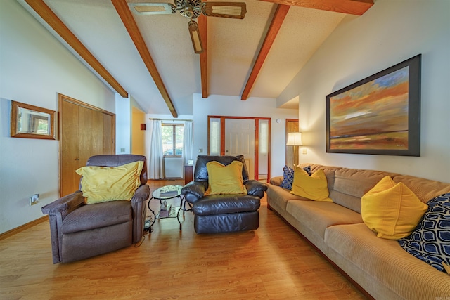 living room with ceiling fan, vaulted ceiling with beams, a textured ceiling, and light wood-type flooring