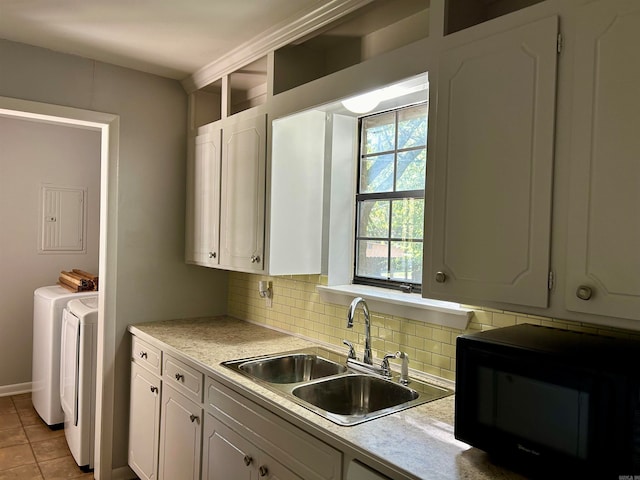 kitchen featuring washer and dryer, white cabinetry, sink, and backsplash